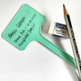 Green plant label with writing, pencil, and eraser on a white background